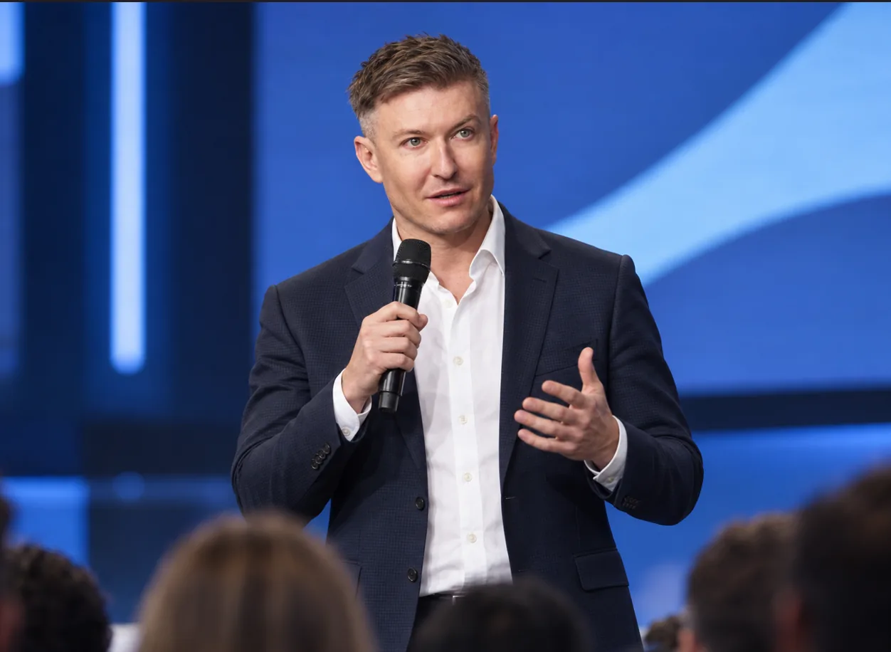 Ілля Зав'ялов на сцені, розвернутий до залу під час конференції